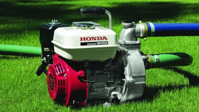 Wide view of pump on a lawn with hoses plugged in. 